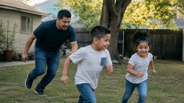 A father chasing his kids in the backyard